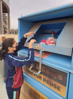 A student is throwing something into the clothes recycling bin.