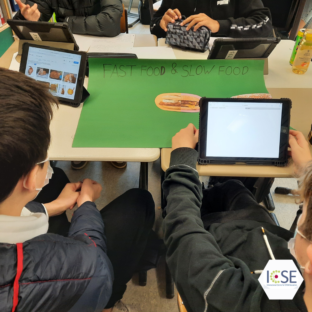 A group of students sit around a desk with tablets.