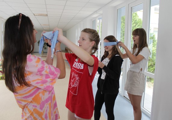 Four students blindfold each other with a cloth.