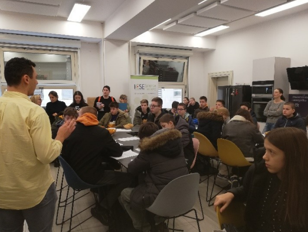 Teacher stands in front of a class and explains something to them